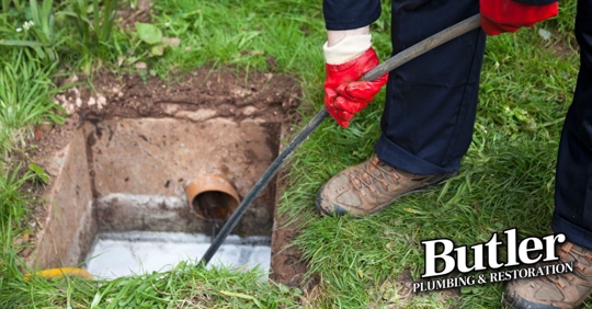 Man with ground open unblocking a drain with a tool
